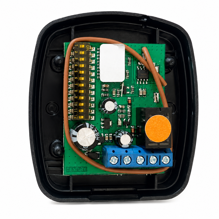 An electronic control module with a green circuit board inside a black plastic housing, featuring a blue terminal block, a white sensor, and a prominent orange circular button.