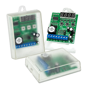 Three electronic timer modules with green circuit boards and clear plastic protective housings, shown on a white background. One module is open to display the front and back, another is closed showing the front view through the translucent housing, and the third is angled to show the back.